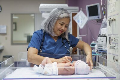 Female Nurse checking a newborn babies heartbeat with a stethoscope