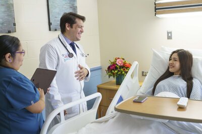 Female Medical Professional is smiling at a female patient that is sitting up in a swing bed