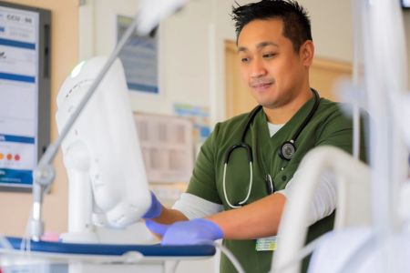 Female Therapist in a female patients room with her. The Therapist is holding an incentive spirometer.